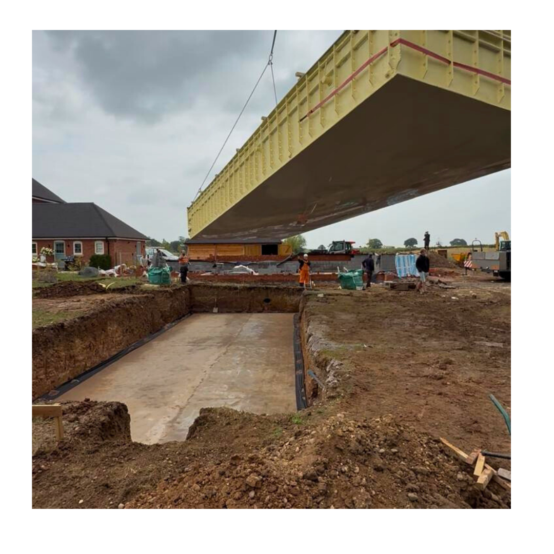 Pool shell being lifted into position by crane over the prepared base