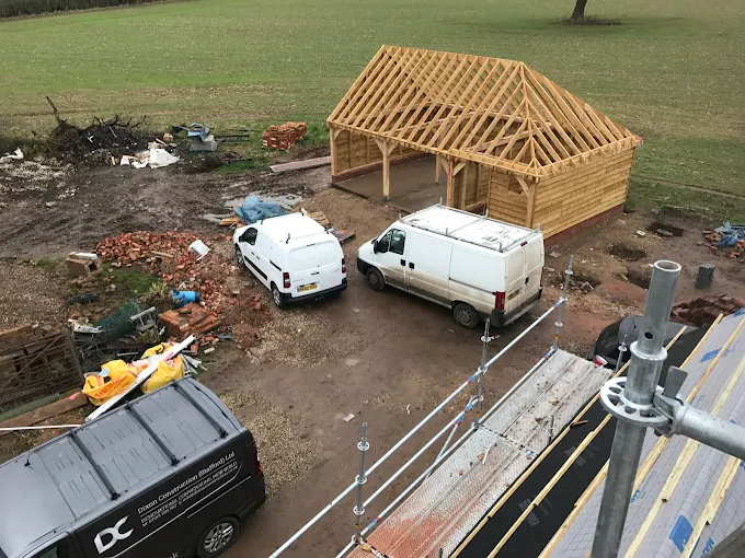 Dixon Construction vans on site beside a timber-frame garage under construction in a Staffordshire field