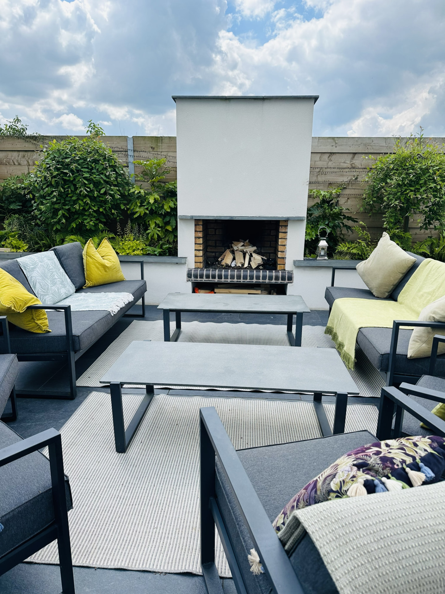 Rendered outdoor fireplace with log store and garden sofas on a porcelain patio in Penkridge