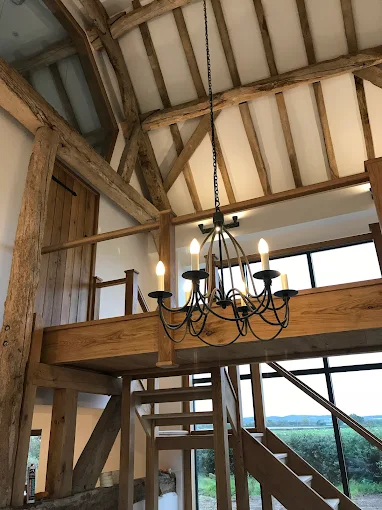 Barn conversion interior with exposed oak beams, oak staircase and wrought-iron chandelier