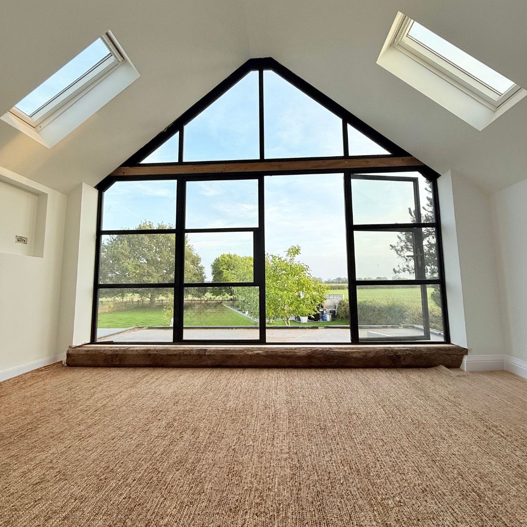 Finished master bedroom with a full-height apex window, reclaimed oak sill and rooflights