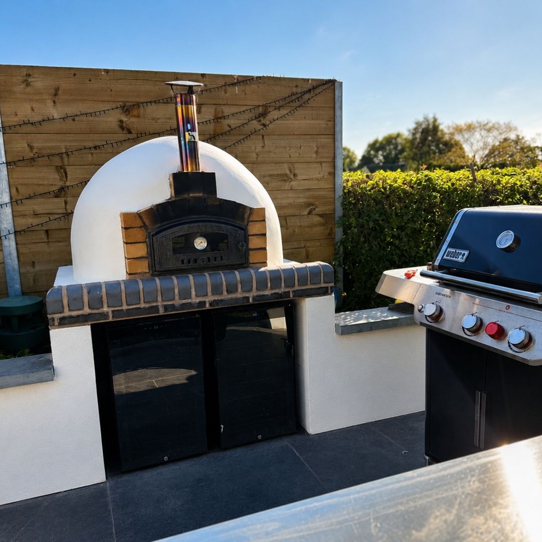 Finished rendered pizza oven with brick arch and flue beside a built-in barbecue in Penkridge