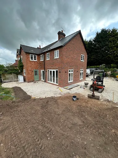 Large red-brick house extension with new windows and doors fitted, scaffolding removed